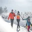 Familie wandert auf einem verschneiten Weg zwischen schneebedeckten Bäumen
