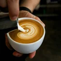 Pouring milk foam into coffee cup to create latte art