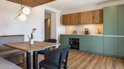 Modern kitchen with green cabinets and wooden table with chairs