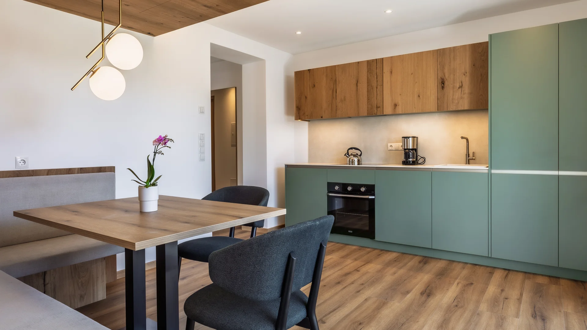Moderne Küche mit grün lackierten Schränken und Holztisch mit Stühlen