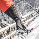 Skifahrer in roter Jacke mit Stöcken auf einem verschneiten Hang