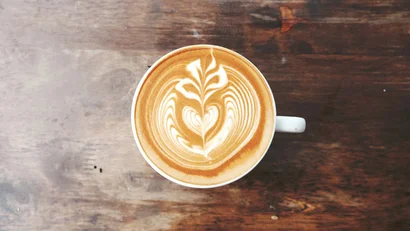 Latte macchiato with heart and leaf design on wooden surface