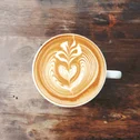 Latte macchiato with heart and leaf design on wooden surface