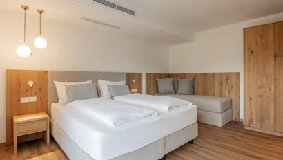 Modern hotel room with double bed, single bed, and wooden furniture