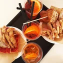 Two ham sandwiches and three drinks with orange slices on a tray
