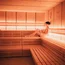 Frau entspannt in moderner Sauna mit Holzverkleidung und warmem Licht