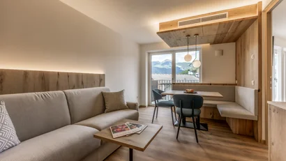 Modern living room with sofa, dining table, and mountain view through window