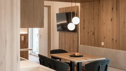 Modern dining area with wooden table, chairs, and wall-mounted TV