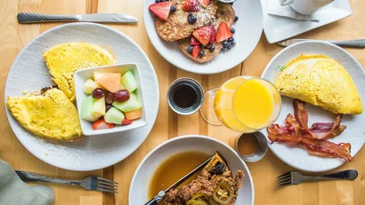 Assorted breakfast plates with omelette, fruit, pancakes, bacon and orange juice