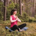 Frau meditiert im Wald auf Yogamatte in Lotusposition