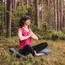 Frau meditiert im Wald auf Yogamatte in Lotusposition