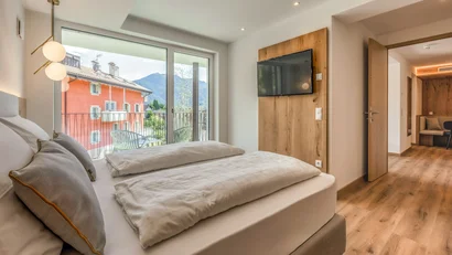 Modern hotel room with double bed, balcony, and mountain view