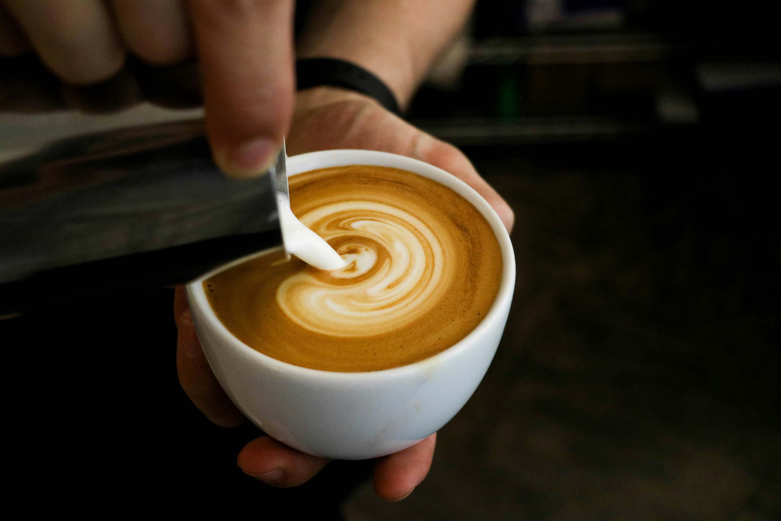 Milchschaum wird in eine Tasse Kaffee für Latte Art gegossen